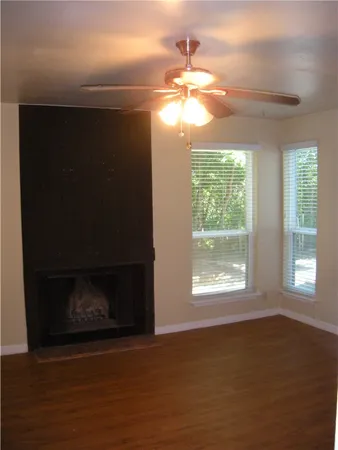 a view of an empty room with wooden floor fireplace and a window