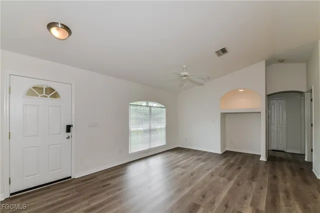 an empty room with wooden floor and windows
