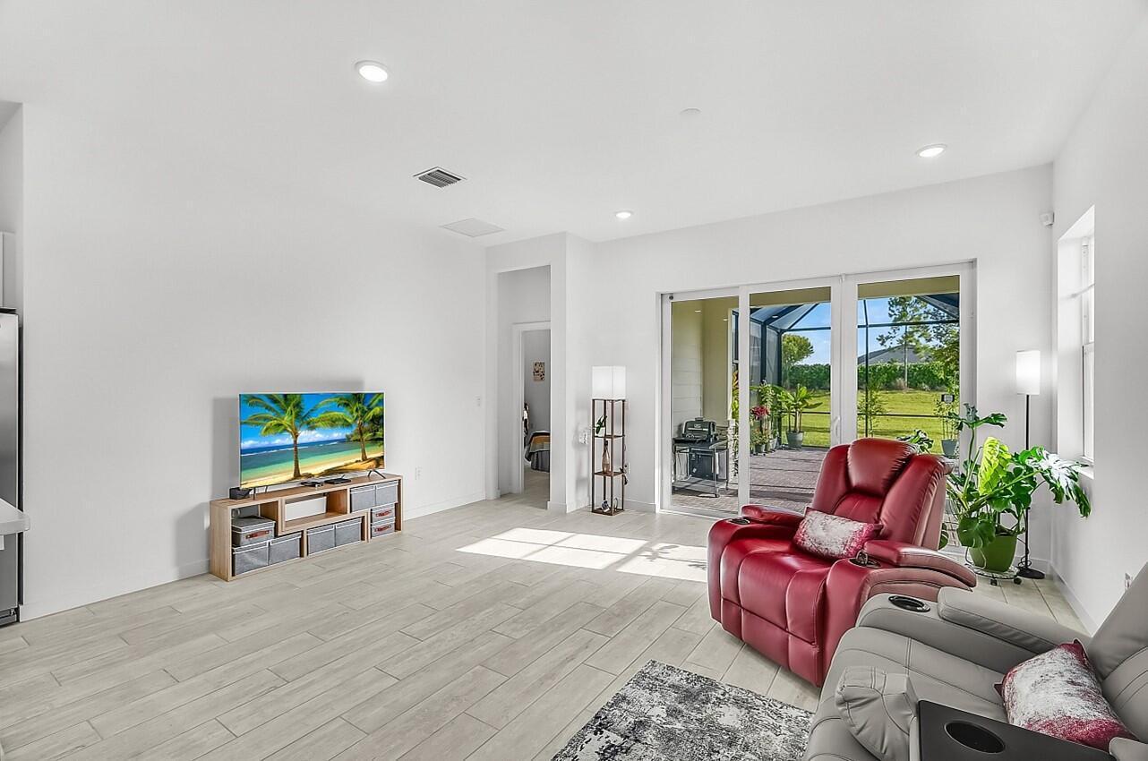19567 Weathervane Way Loxahatchee, FL 33470 - Photo 10 of 49 a living room with furniture floor to ceiling window hardwood floor and a flat screen tv