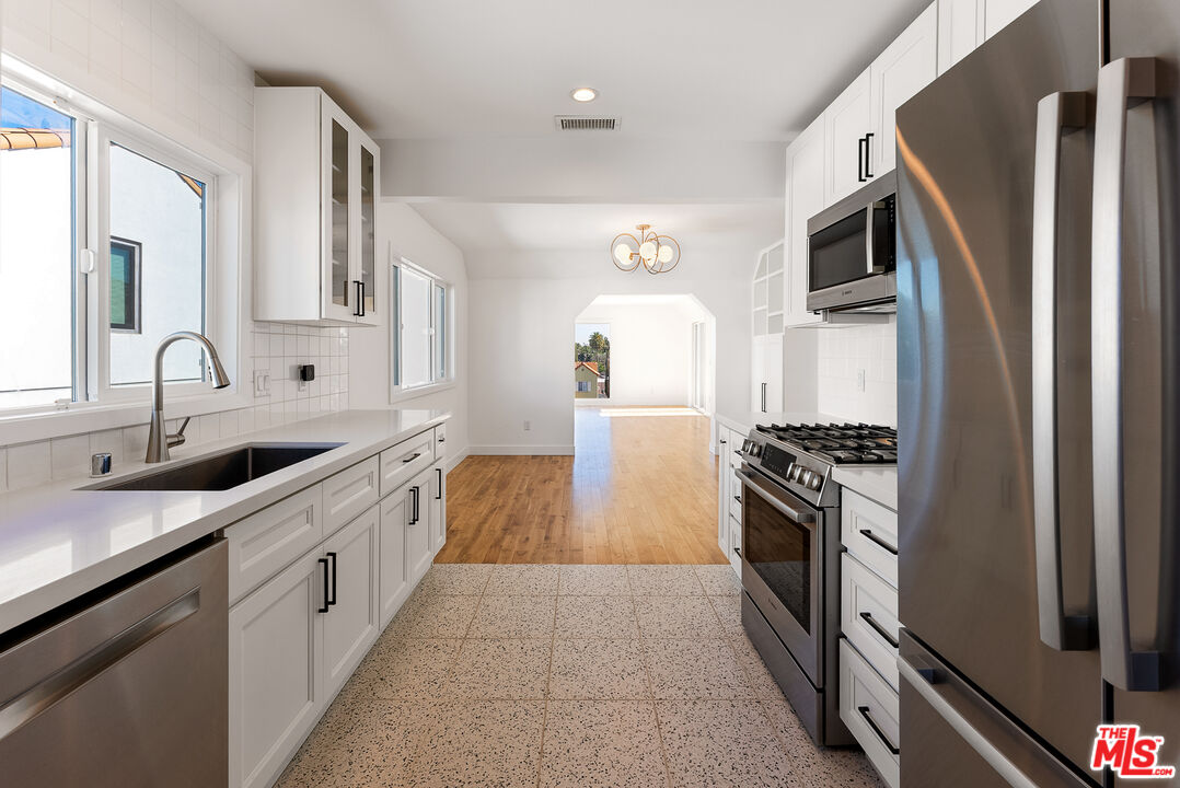 1253 South Rimpau Boulevard Los Angeles, CA 90019 - Photo 13 of 71 a kitchen with stainless steel appliances granite countertop a sink stove and refrigerator