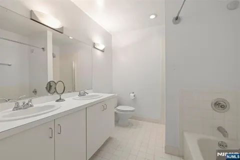 a bathroom with a toilet a sink a tub and mirror