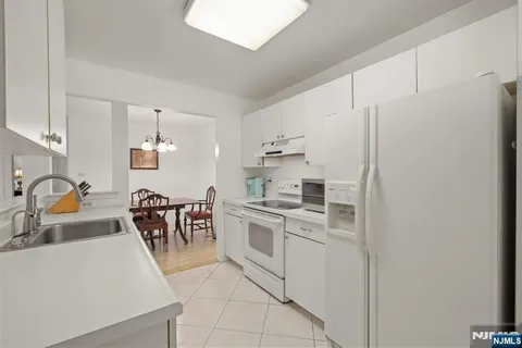 a kitchen with stainless steel appliances a white stove top oven and white cabinets next to a window