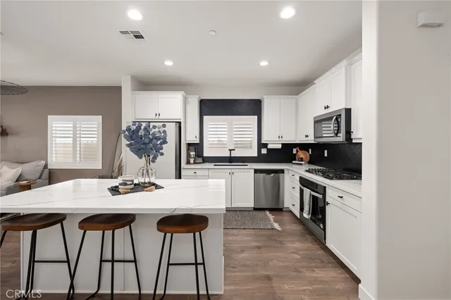 a kitchen with stainless steel appliances kitchen island granite countertop a kitchen island a stove a table and chairs