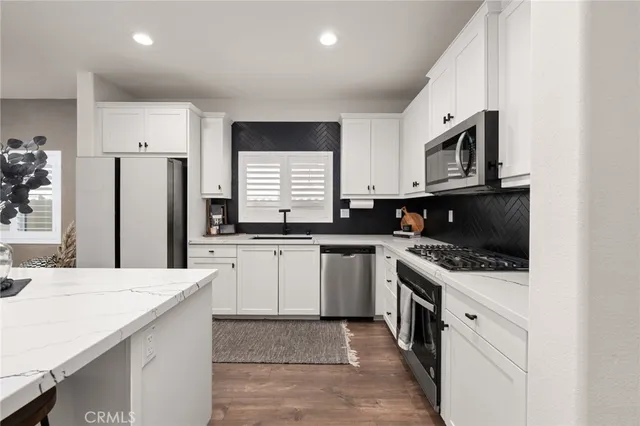 a kitchen with stainless steel appliances kitchen island granite countertop a refrigerator and a stove top oven