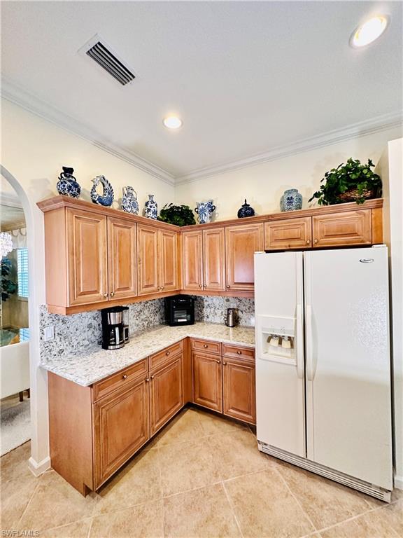16152 Parque Lane Naples, FL 34110 - Photo 12 of 49 Kitchen with light tile patterned flooring, crown molding, and white fridge with ice dispenser