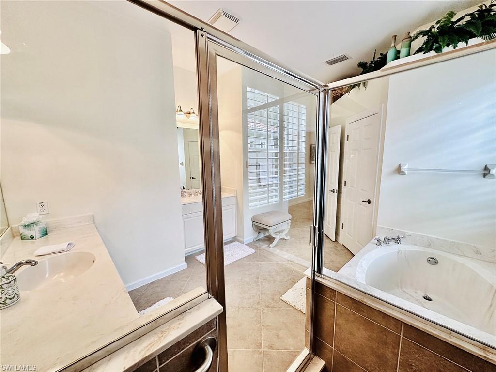 16152 Parque Lane Naples, FL 34110 - Photo 19 of 49 Bathroom featuring vanity, tile patterned floors, and a relaxing tiled tub