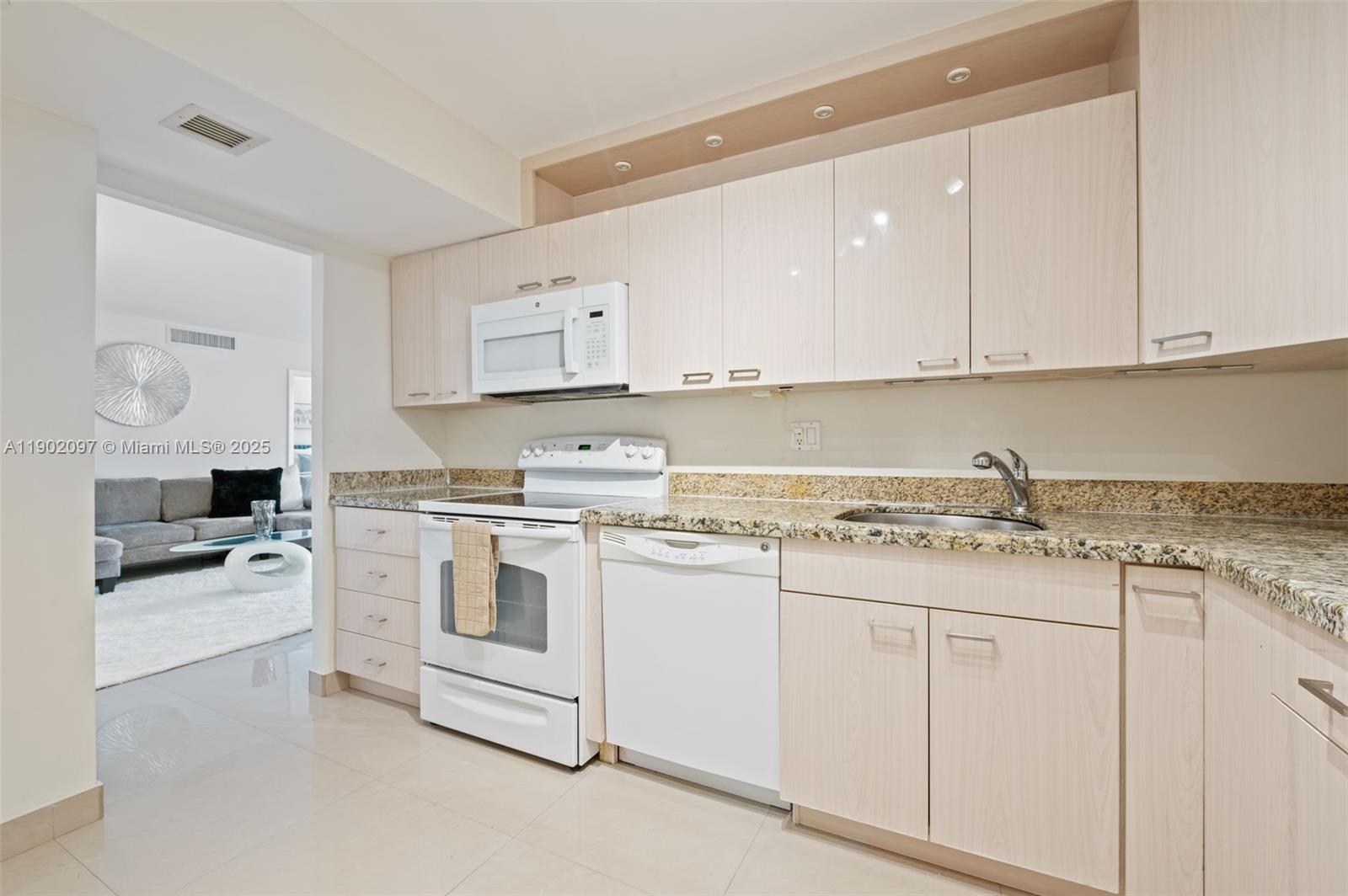 1833 South Ocean Drive, Unit 809 Hallandale Beach, FL 33009 - Photo 13 of 26 a kitchen with granite countertop white cabinets and white appliances