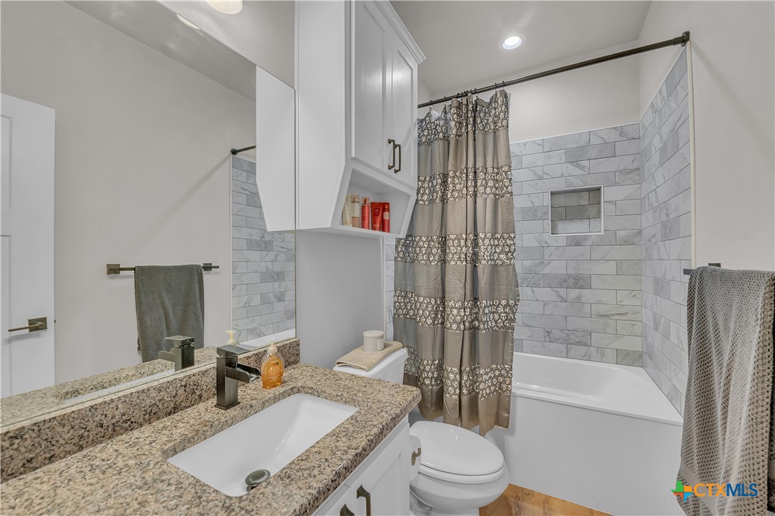 1601 Badger Lane Lampasas, TX 76550 - Photo 15 of 29 a bathroom with a granite countertop bathtub sink vanity mirror and toilet