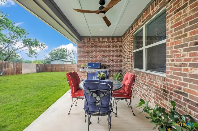 a patio with table and chairs and potted plants