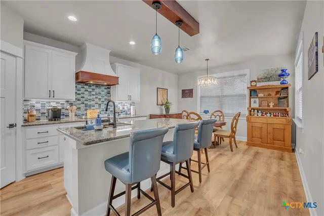 a kitchen with stainless steel appliances kitchen island granite countertop a table chairs sink and cabinets