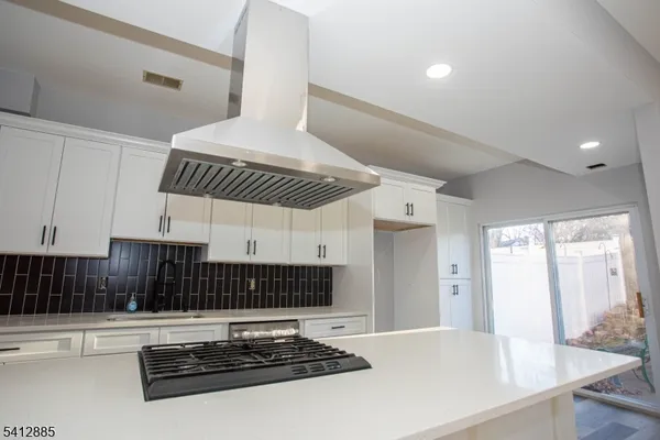 a kitchen with stainless steel appliances a stove a sink a refrigerator white cabinets and wooden floor