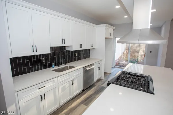 a kitchen with stainless steel appliances a sink a stove and white cabinets