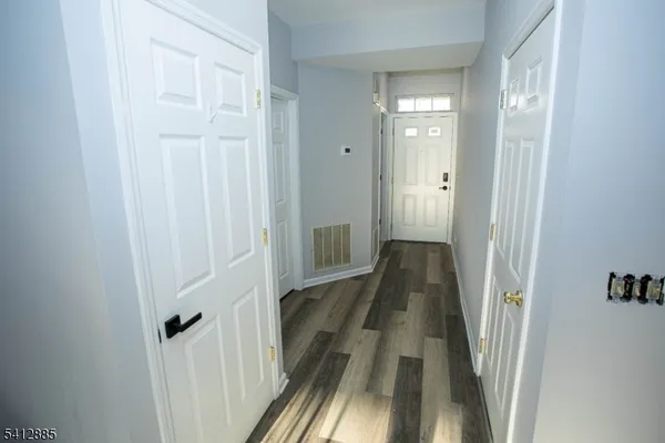 a view of a hallway with wooden floor and a bathroom