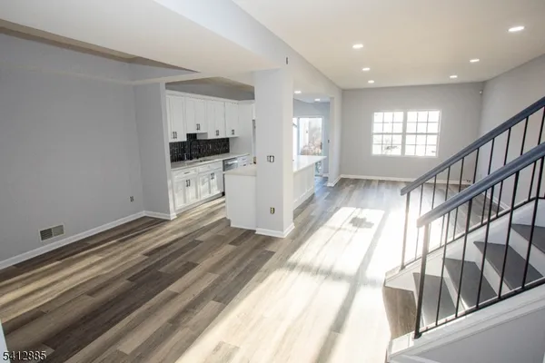 a hallway with white cabinets and wooden floor