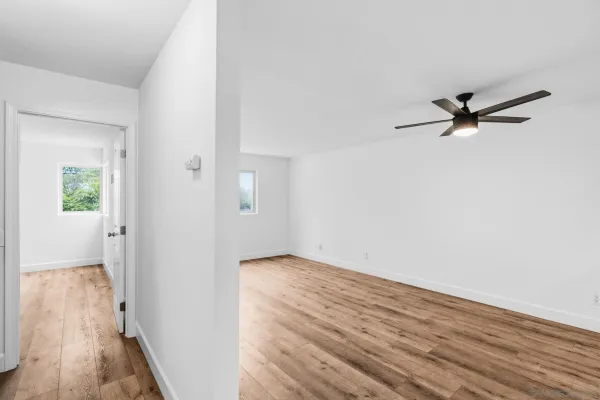 a view of a room with wooden floor and a ceiling fan