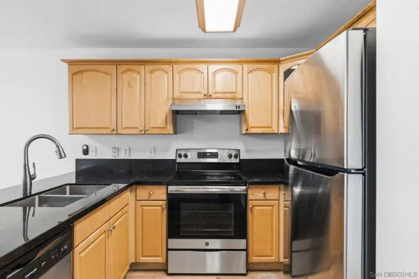 a kitchen with stainless steel appliances granite countertop a stove a refrigerator and a sink