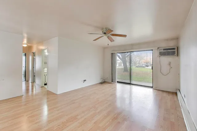 a view of an empty room with a window and wooden floor