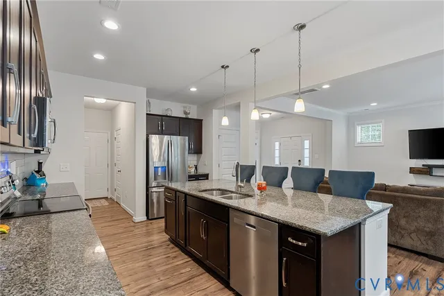 a open kitchen with stainless steel appliances granite countertop a granite counter tops a stove a sink and a refrigerator