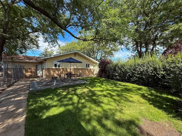 a backyard of a house with table and chairs under an umbrella