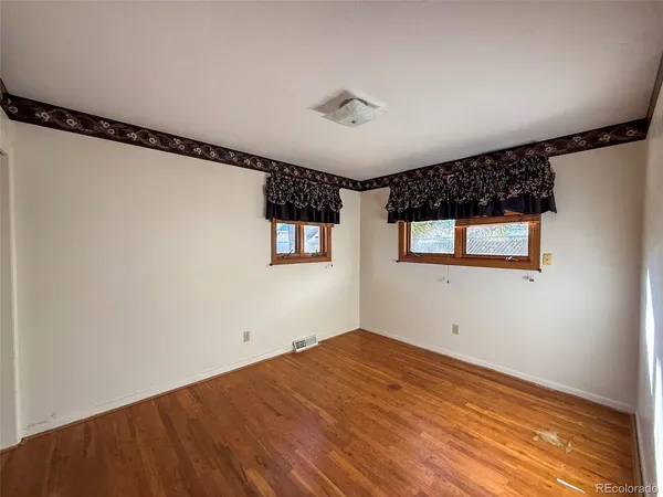 a view of a big room with wooden floor and windows
