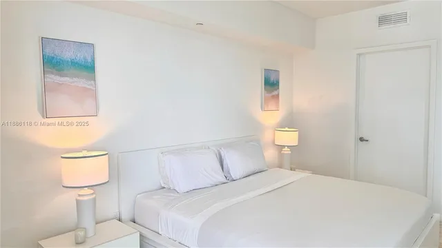 a white bed sitting in a bedroom and lamp