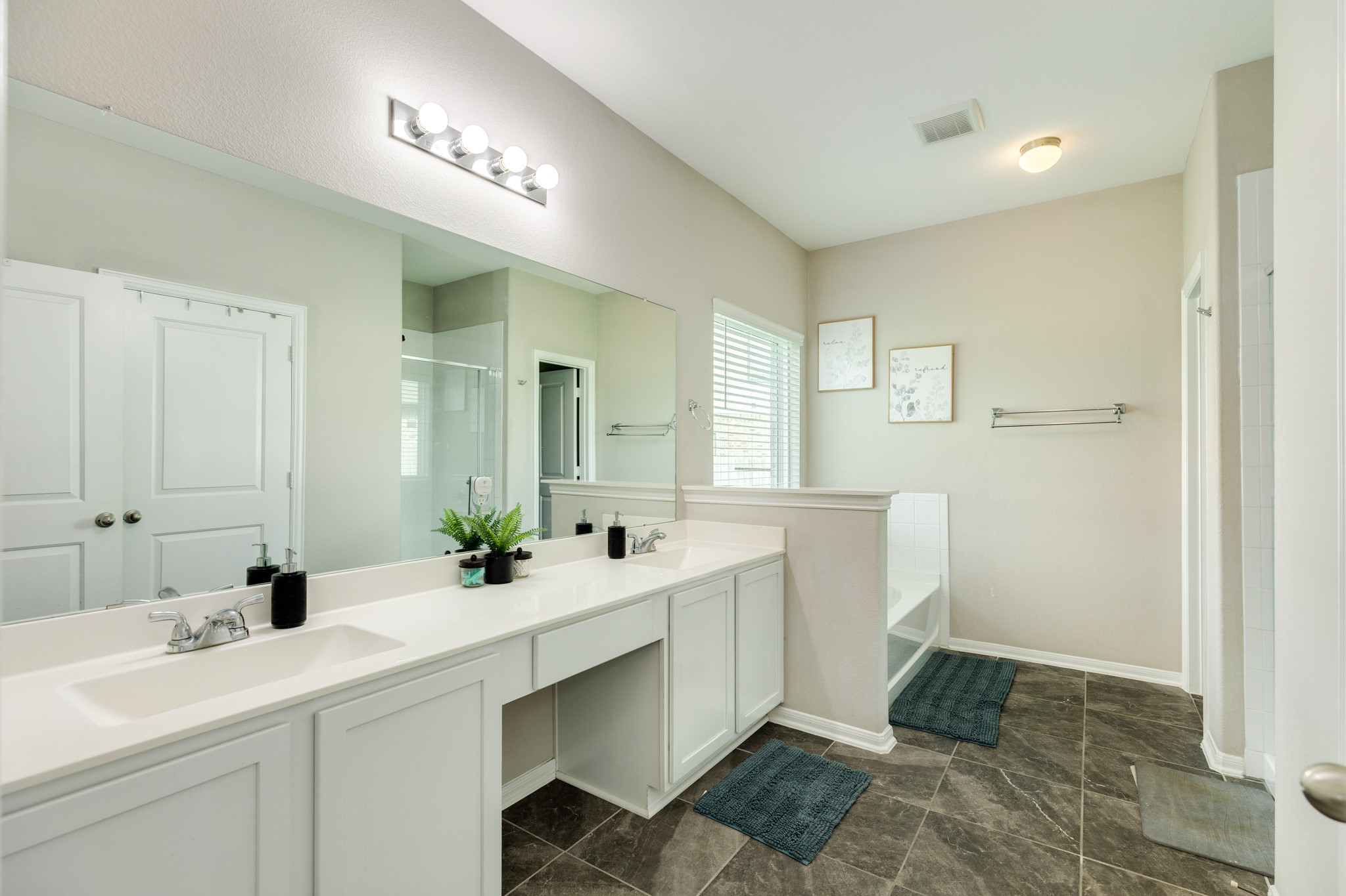 2446 Palisade Crst Drive Rosharon, TX 77583 - Photo 18 of 30 Bright and spacious bathroom with dual sinks, modern lighting, and a large mirror. Features a walk-in shower, bathtub, and ample storage. Neutral tones and natural light create a relaxing atmosphere.