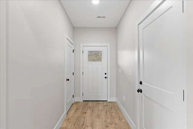 a view of a hallway with wooden floor and a bathroom