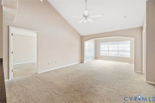 an empty room with chandelier fan and windows