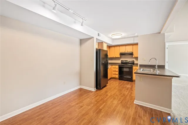 a kitchen with stainless steel appliances granite countertop a refrigerator a stove and a wooden floors