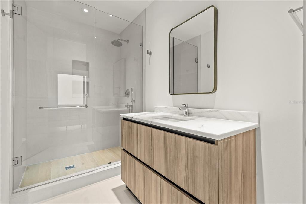 1020 Sunset Point Road, Unit 108 Clearwater, FL 33755 - Photo 20 of 62 a bathroom with a shower sink and mirror