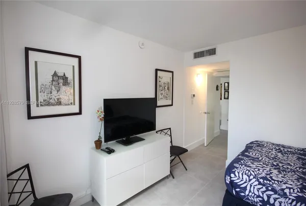 a living room with a flat screen tv on dresser and a table