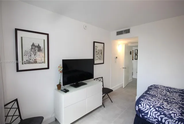 a living room with a flat screen tv on dresser and a table