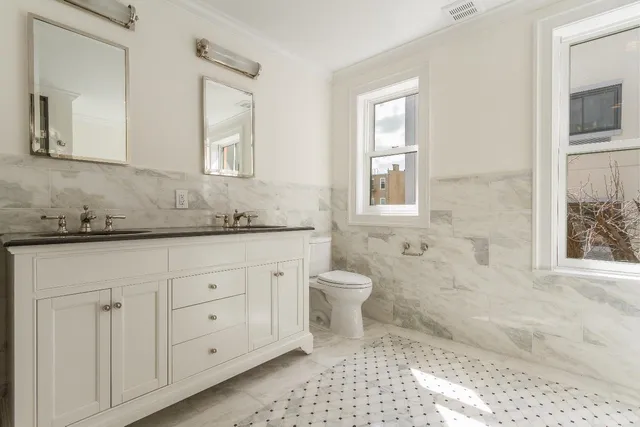 a bathroom with a granite countertop toilet sink and mirror