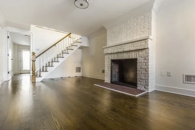 an empty room with wooden floor fireplace and windows