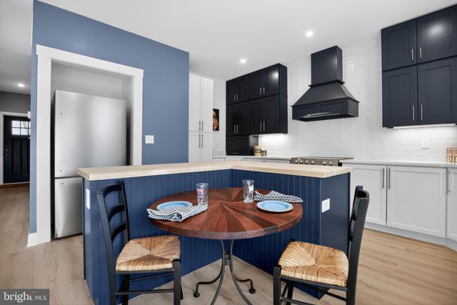 a kitchen with stainless steel appliances kitchen island granite countertop a table chairs in it and wooden floors