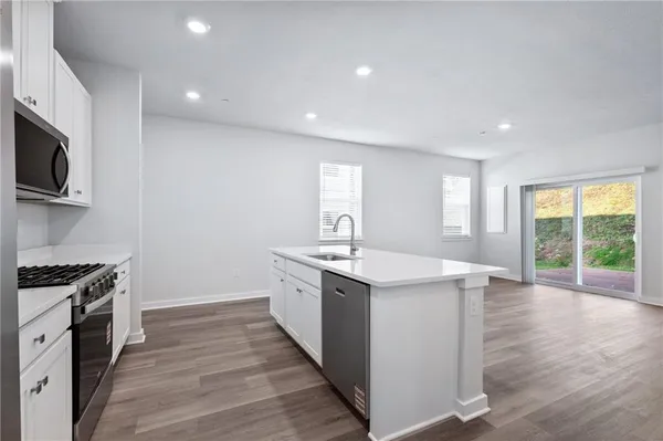 a kitchen with a sink stove and wooden floor