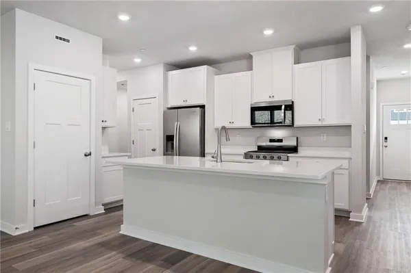 a kitchen with stainless steel appliances a refrigerator sink and white cabinets
