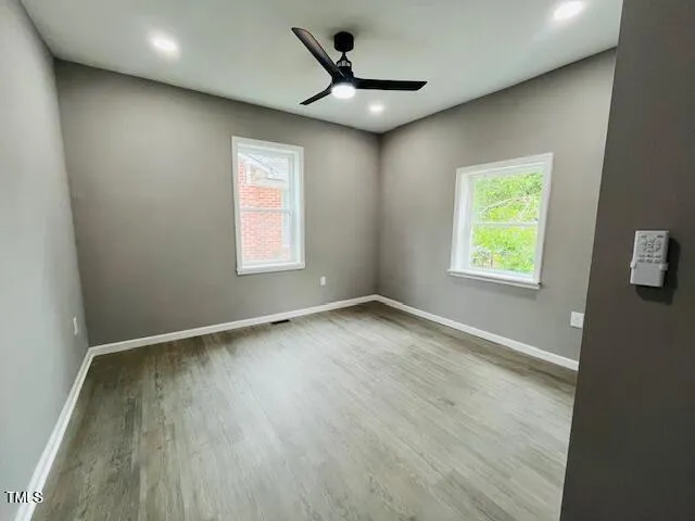 an empty room with wooden floor and windows