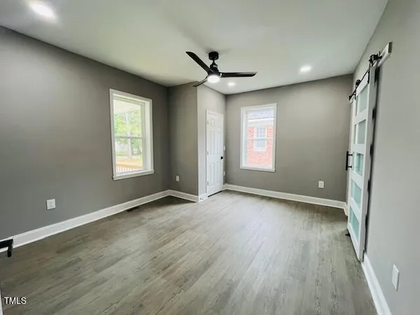 a view of an empty room with wooden floor and a window