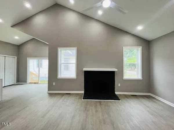 an empty room with wooden floor and a fireplace