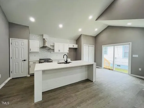 a large kitchen with stainless steel appliances a large counter top a stove and a refrigerator