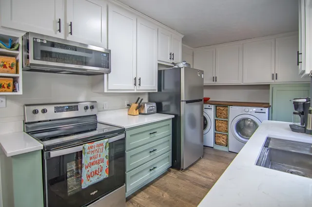 a kitchen with cabinets a sink dishwasher a dining table and chairs with wooden floor