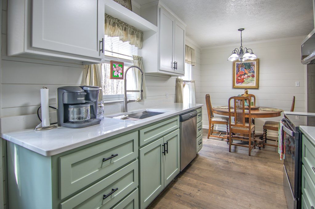 10933 Us Highway Hamilton, GA 31811 - Photo 17 of 44 a kitchen with cabinets a sink dishwasher a dining table and chairs with wooden floor