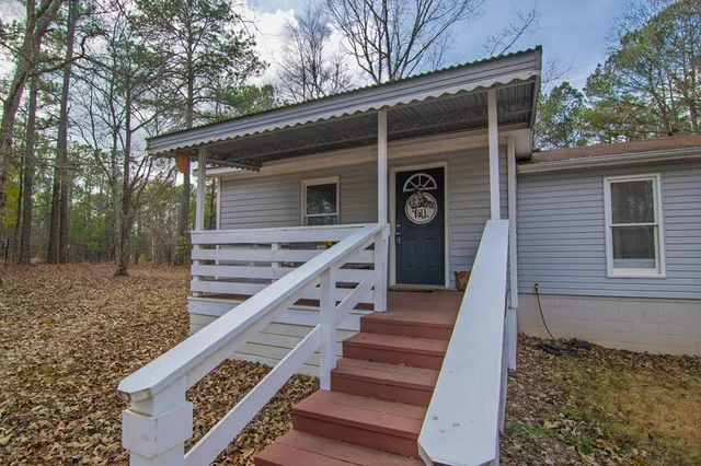 a view of a house with wooden deck and a forest