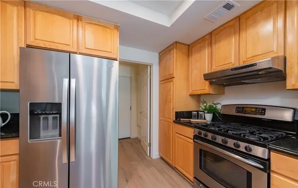 a kitchen with stainless steel appliances granite countertop a refrigerator and a stove top oven