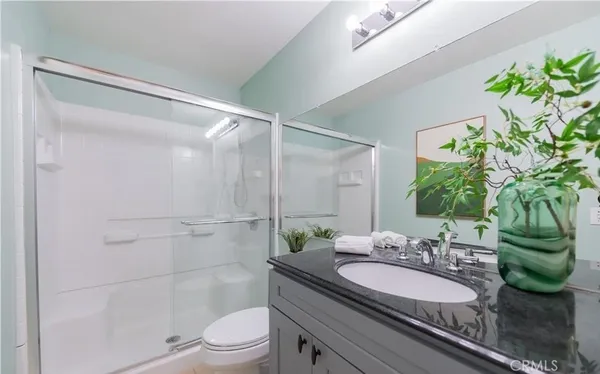 a bathroom with a granite countertop sink a toilet a mirror and shower