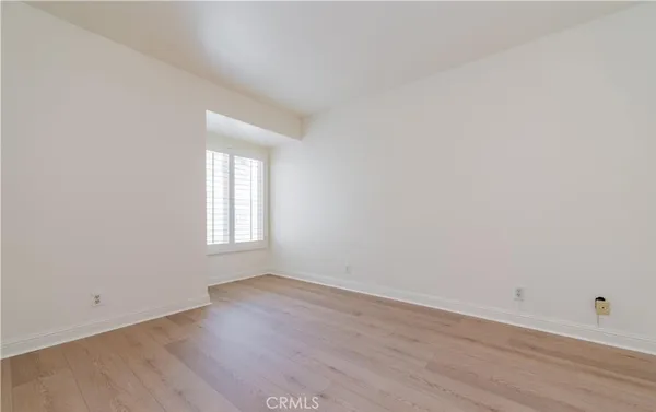 an empty room with wooden floor and window