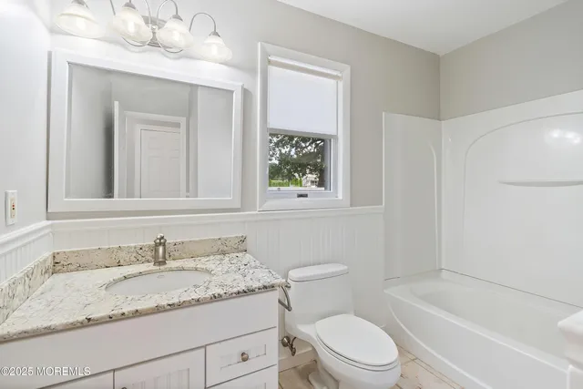 a bathroom with a granite countertop sink toilet mirror and bathtub