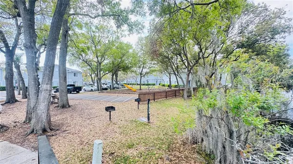 a park view with a barbeque and large trees