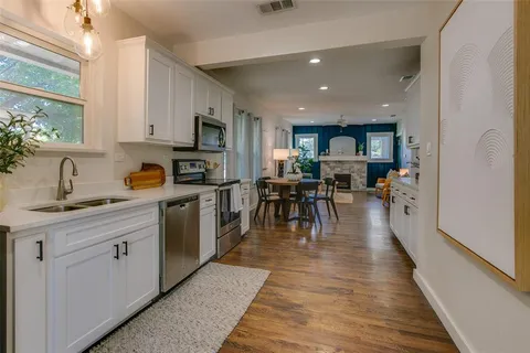 a kitchen with stainless steel appliances granite countertop wooden cabinets a sink a stove a dining table and chairs